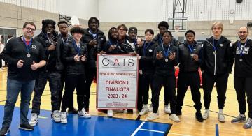 Group of basketball players in sweatsuits holding a banner